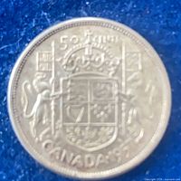 reverse of 1957 Canada 50 cent coin showing arms and date