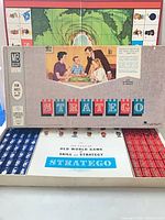 Closed box on game board with opened tray showing red and blue pieces