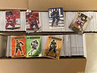 Top view of two-row box filled with white card stacks; six sample cards displayed on top including UD Dazzlers and base cards