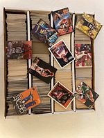 Overview of five-row storage box filled with loose basketball cards; several sample cards laid on top