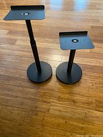 Both speaker stands at different heights on wood floor