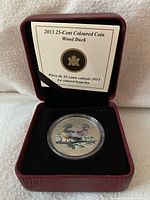Coin in open maroon clamshell case showing specification card and capsule