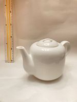 Profile view of white teapot showing shape, spout, handle