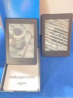 Front view of both Kindle Paperwhite units beside original box insert