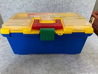 Front of blue Battat tackle box with yellow lid, red handle, green latch