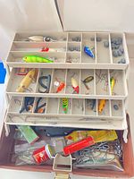 Open tackle box showing trays of lures, hooks and sinkers