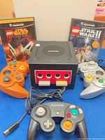 Front view of GameCube console, three controllers, two LEGO Star Wars games