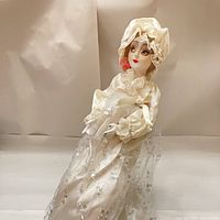 Full view of doll in satin gown on stand