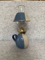 Full view of ceramic oil lamp showing base, brass burner, glass chimney and shade