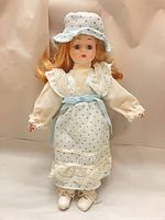 Front view of porcelain doll standing with bonnet on