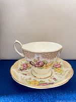 Teacup on saucer showing pattern, gold trim and floral design