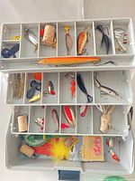 Open tackle box showing top and middle trays filled with lures