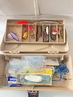 Open tackle box showing upper tray lures and lower compartment tackle