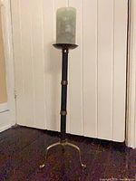 Full view of tall brass candlestick with candle