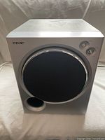 Front view of subwoofer showing grille, bass port, controls