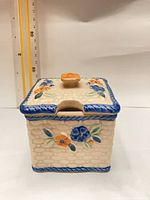 Front view showing floral design, blue trim, orange knob