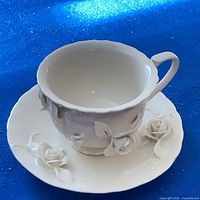 Teacup and saucer showing interior and relief roses