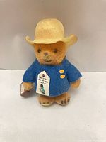 Front view showing coat, hat, suitcase, chest tag