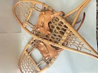 Both wooden snowshoes showing frames, webbing, and leather bindings