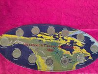 Front of oval board displaying 12 mounted coins