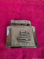 Front view showing chrome lighter with embossed sailing ship