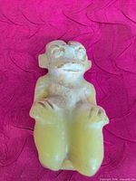 Front view of small green jade figurine showing seated figure details