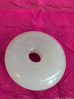 Front view of polished white jade donut pendant