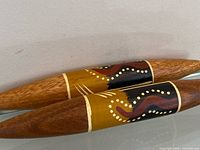 Two tapered wooden clapsticks with Aboriginal painted design side by side