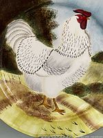 Close-up of rooster artwork on platter