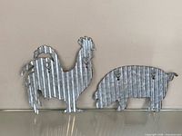 Front view of rooster and pig corrugated metal silhouettes showing keyhole hangers