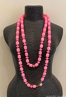 Full view of long pink bead necklace on bust