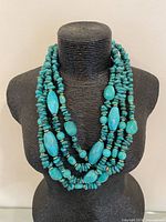 Front view of necklace draped on bust showing three strands and bead shapes