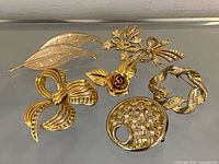 overview of six gold-tone brooches laid out
