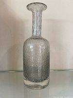 Front view of clear textured glass bottle showing overall form and bubble pattern