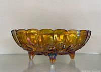Side view of Indiana Glass marigold carnival glass oval bowl on four feet