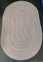 Full view of oval braided rug on dark floor