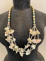 Necklace displayed on bust, showing multi-strand shell chip arrangement