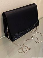 Front view of black satin purse with chain strap