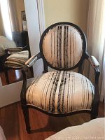 Front view of carved French chair showing silk upholstery with black and cream vertical stripes and floral patterns.