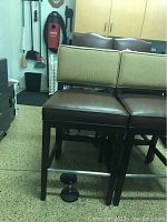 Two side angles of matching bar stools showing brown cushioned seats, beige fabric backrests, dark wooden legs, and metal footrests.