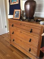 Front angled view of a solid oak dresser with three drawers and metal handles, showing restored natural wood finish and moderate wear.