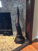 Full view of one bronze horn sculpture on hearth showing overall shape and height