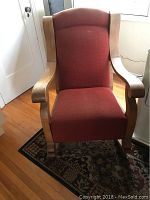 Front view of antique rocking chair with red upholstery and solid wood frame.