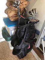 Black Nike golf bag with red trim containing multiple golf clubs including Callaway irons, Warrior hybrid with headcover, and others.