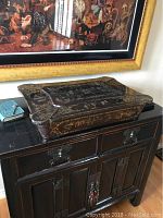Top view of antique Chinese sewing box showing scalloped edges and hand painted floral motifs in gold on black lacquer.