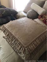 Three custom 24x24 silk pillows with fringe trim and floral jacquard patterns, stacked on furniture