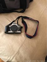 Front view of the Canon EOS Rebel G camera with Canon strap and black carrying bag in the background.