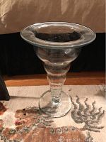Full view of tall clear glass vase on carpet showing overall shape and wide mouth