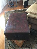 Top-down view of the rectangular antique leather trunk showing worn reddish leather surface.