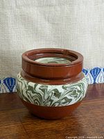 Front view of reddish-brown pottery jar with marbled band